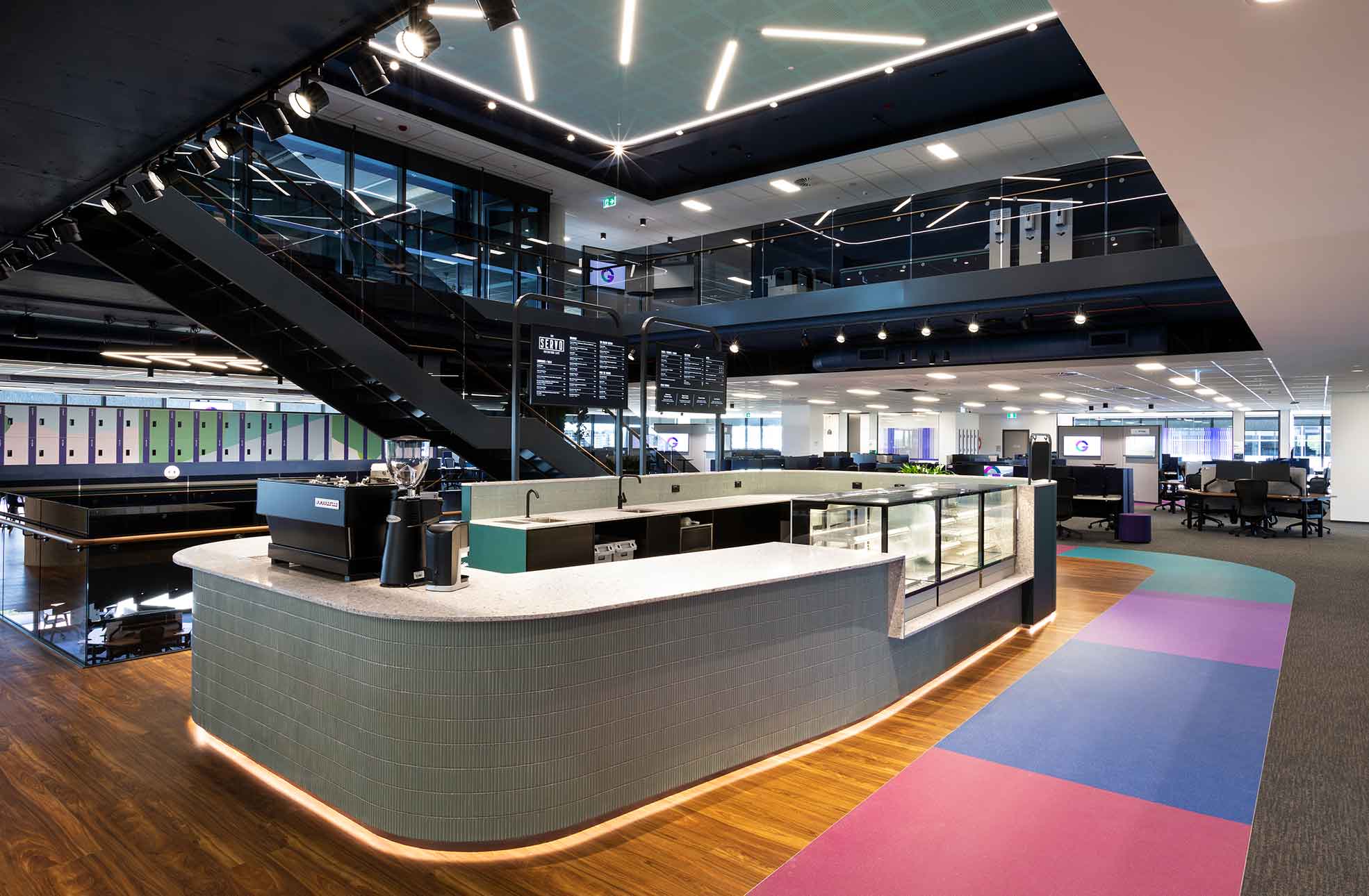 Office fitout with kitchen, coffee machine, stairs to upper floor & workstations in background